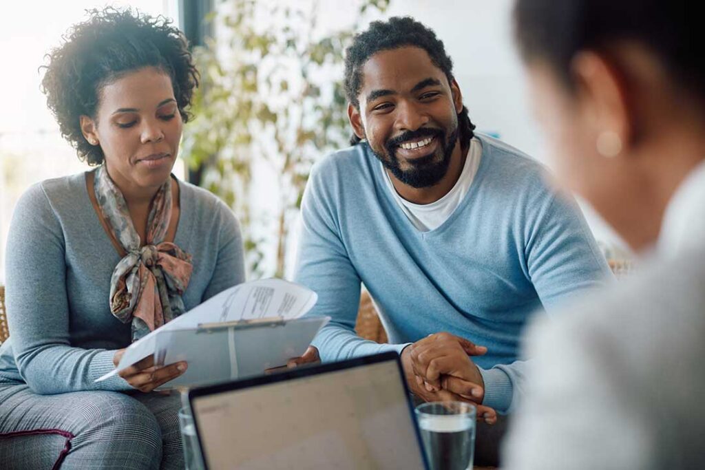 A diverse group of adults studying health insurance documents together at a kitchen table.