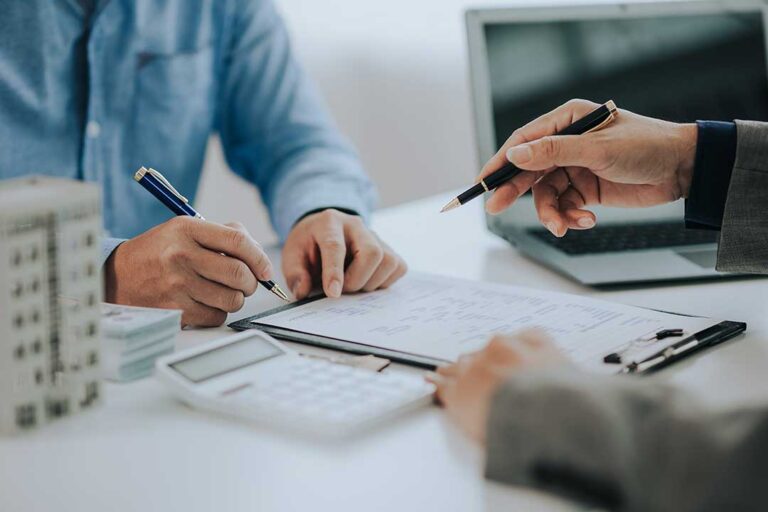 A patient reviews health insurance paperwork beside a physician discussing reconstructive surgery options.