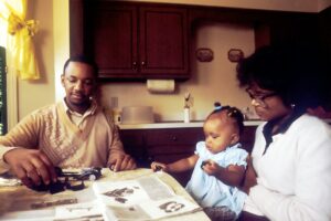 Family reviewing a life insurance beneficiary form and organized financial documents at a kitchen table.