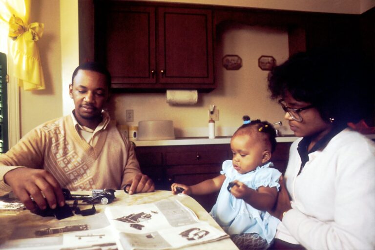 Family reviewing a life insurance beneficiary form and organized financial documents at a kitchen table.