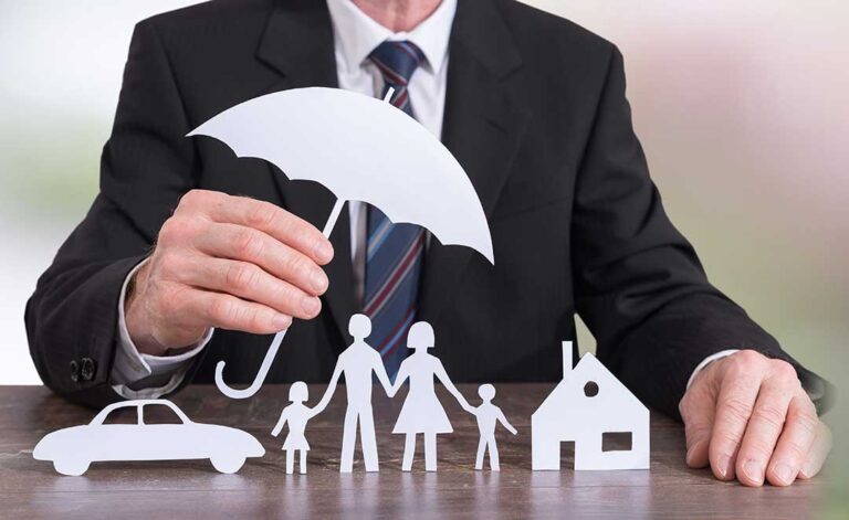 A household reviewing several insurance policy documents beside a laptop and home inventory checklist.